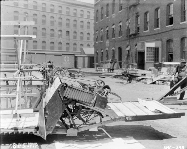 Binder set up in a yard near factory buildings. A man stand is standing on the right.