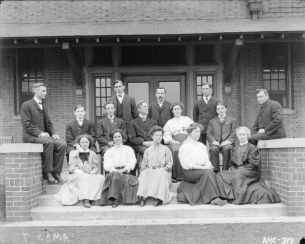 Group of men and women posing outdoors on the steps of the club house.