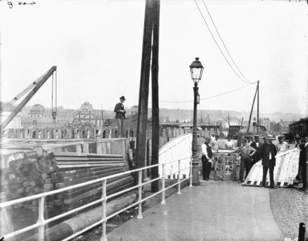 View of men on a dock with binder. There are town buildings in the background.