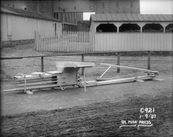 Horse-powered push press and hay press displayed outdoors at Champion Works.
