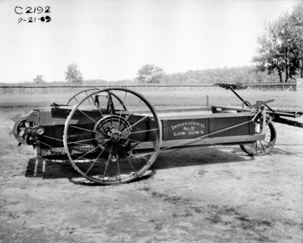 Right side view of a manure spreader in a yard. In the background is a fence.