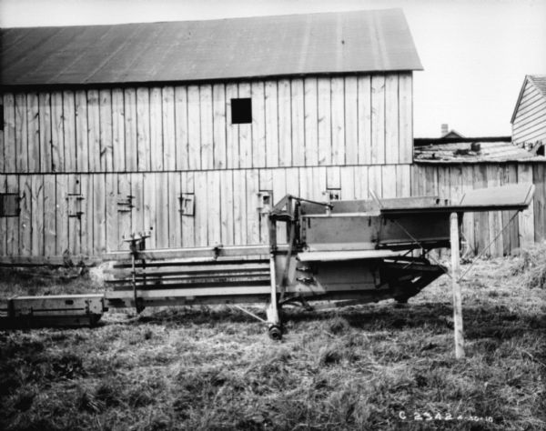View across yard towards powered (this part of the operation is not shown) hay press in front of a barn at Springfield Works.