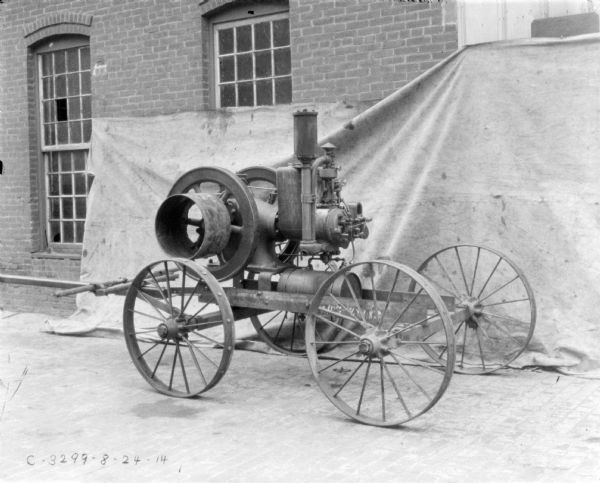 Engine set up outdoors in front of a backdrop against a brick factory building.