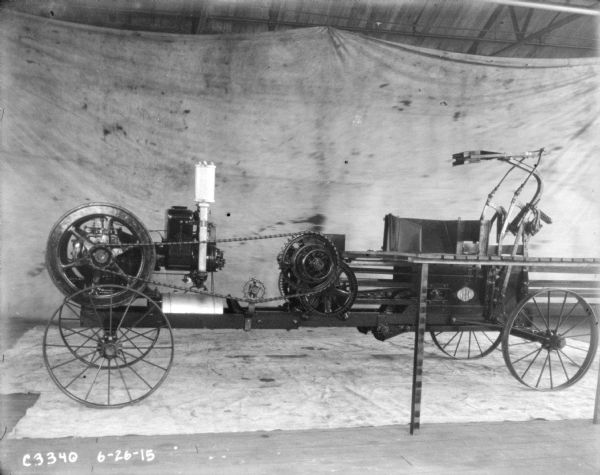 Powered hay press set up in front of a backdrop on factory floor.