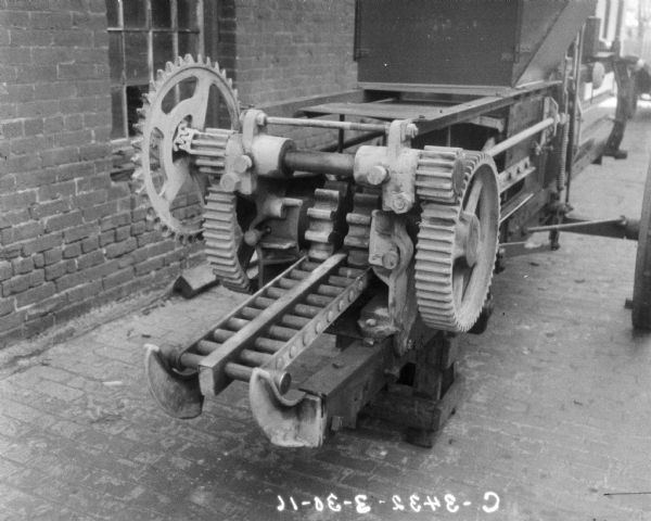 Close-up of powered hay press set up outdoors near factory building.
