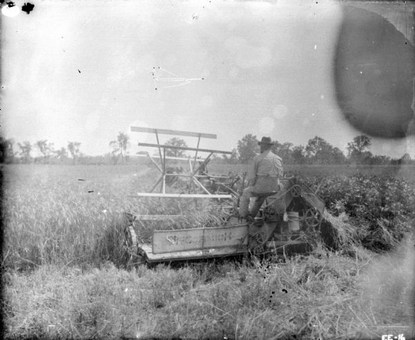 Man working in field on a well-used horse-drawn McCormick binder.