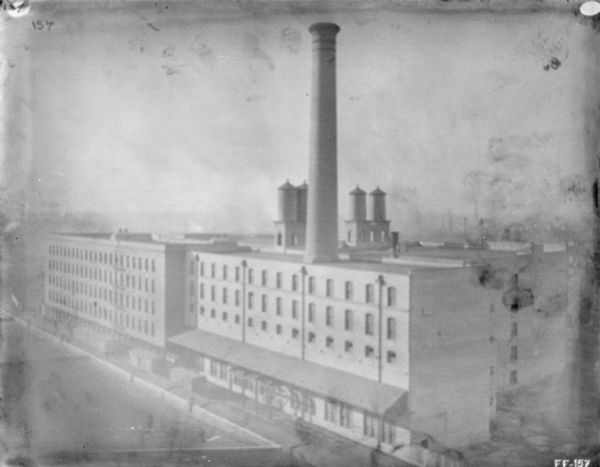 Elevated view of buildings at McCormick Works. On top of the building in the foreground is a large smokestack, and four water towers behind it on the top of the flat roof.