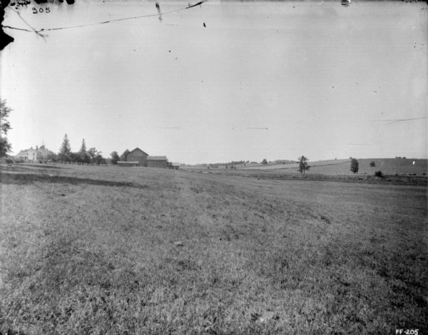 View across field towards farm buildings in the background on the left.