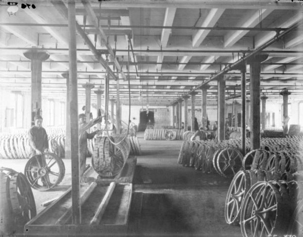 Interior view of men working in a large room with mower wheels.