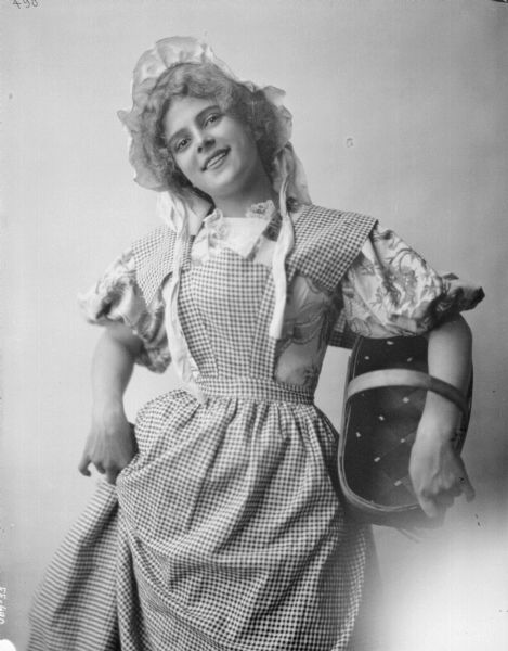 Three-quarter length portrait of a young girl posing with a basket.