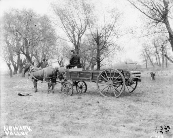 Man using horse-drawn manure spreader in Newark Valley. Trees are in the background.