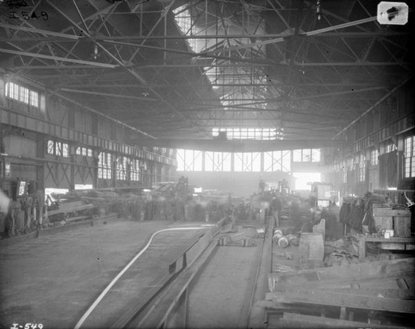 Interior view of foundry mold pouring area. Men are working in the background.