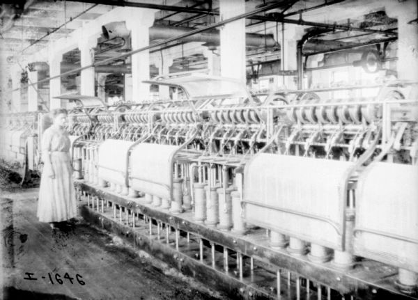 View of young woman standing on factory floor near Twine Machines.