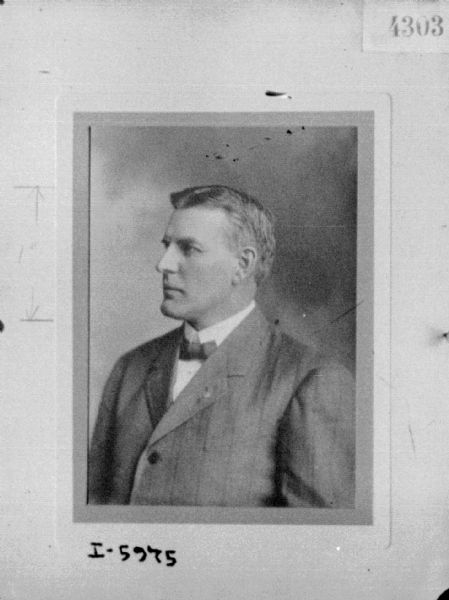 Waist-up formal studio portrait of a man wearing a suit and tie.