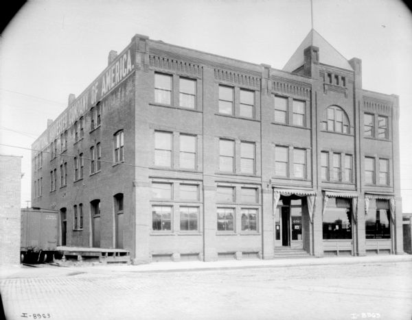 View from street of a dealership. On the left side of the building is a railroad car which is near the loading dock.