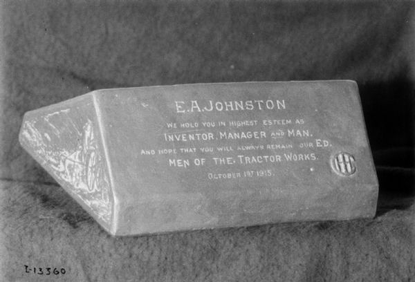 Tribute to E.A. Johnston. Text on block reads: "We hold you in highest esteem as inventor, manager and man. And hope that you will always remain our Ed. Men of the Tractor Works. October 1st 1915." The IHC logo is on the right.