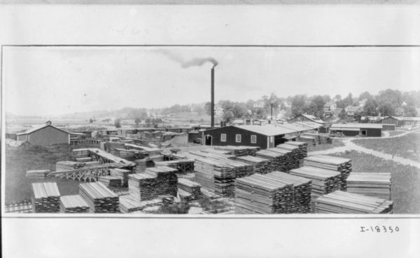 Elevated view of lumber yard. Houses are on a hill in the far background.