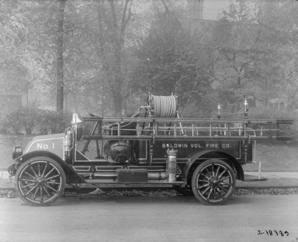 Model F 1919 fire truck parked along curb. Painted on the side: "No. 1," and "Baldwin Vol. Fire Co."