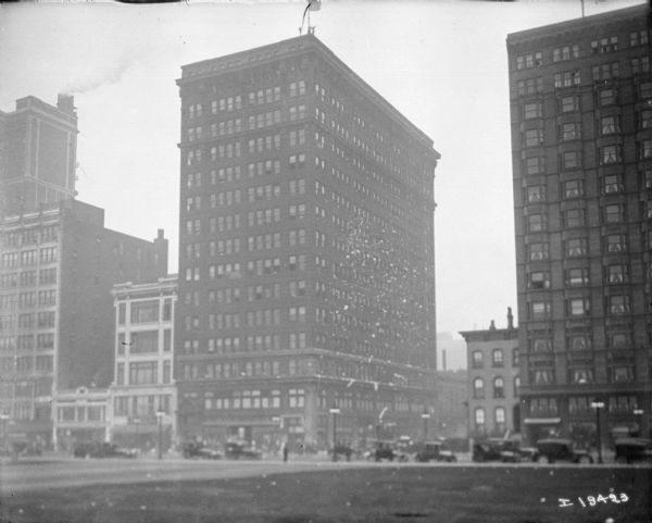 Tickertape parade in a city. There appear to be people standing on the edge of the roof of the building in the center, standing near the base of a flagpole. This may be the International Harvester building.