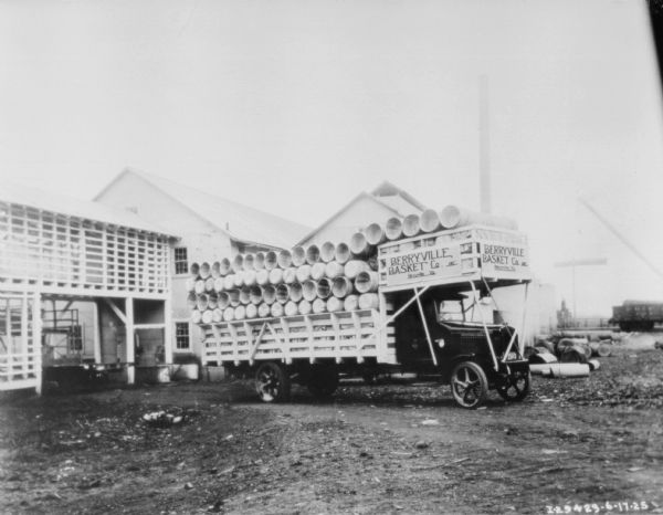 A truck stacked with baskets is parked in the yard near a large building. A sign on the truck reads: "Berryville Basket Co. Inc. Berryville Va."