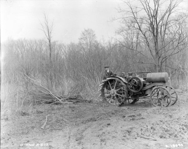 A man is using a Titan tractor and a chain to clear brush.