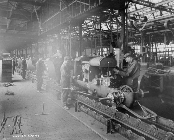 Group of men working on equipment in a manufacturing area on a factory floor.