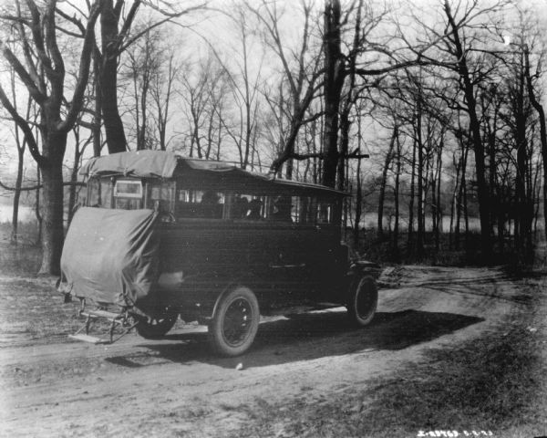 Three-quarter view from right rear of a truck adapted with a tent attached to the back while moving down a dirt road.