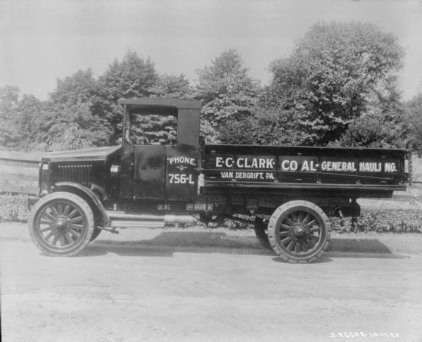 Left side profile view of a delivery truck parked on a road. The sign painted on the side of truck bed reads: "E.C. Clark Coal Hauling. Vandergrift, PA."