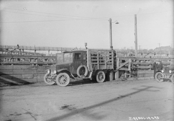 Men standing near a delivery truck in a stockyard.