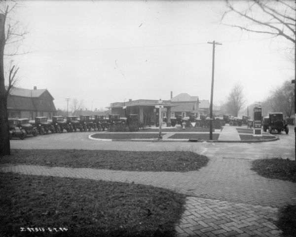 View across yard towards a semi-circle of delivery trucks parked at a service station.
