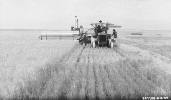 Slightly elevated view of a man using a tractor drawn binder in a field.
