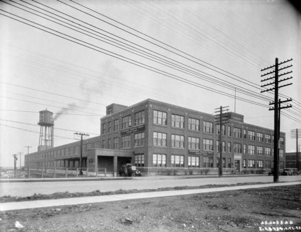 View from across street of the IH Printing Plant. A man is standing near a truck parked at the loading dock on the left.