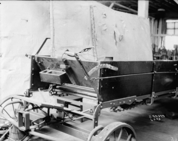 Close-up view of a manure spreader in front of a backdrop in what is probably a factory.