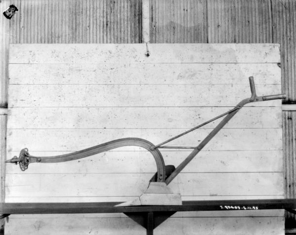 Left side profile view of a walking plow displayed on a table.