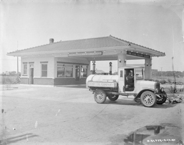 View of a man in a Derby Oil Company truck at the Park Filling Station.