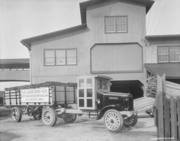 A E.S. Adkins & Co. delivery truck with a trailer at a lumber yard.