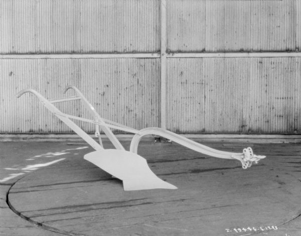 Walking plow on display on a wood floor.