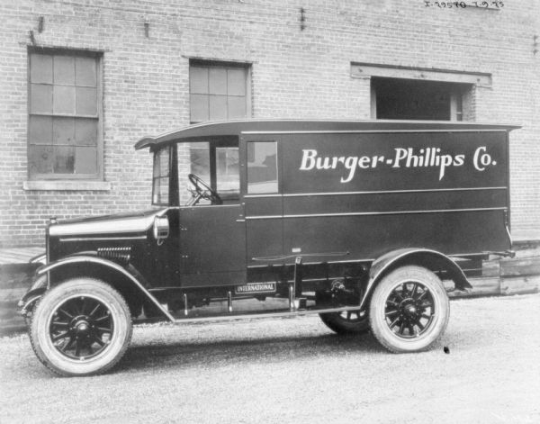 Driver's side view of a delivery truck parked in front of a brick building. The sign painted on the side reads: "Burger-Phillips Co."