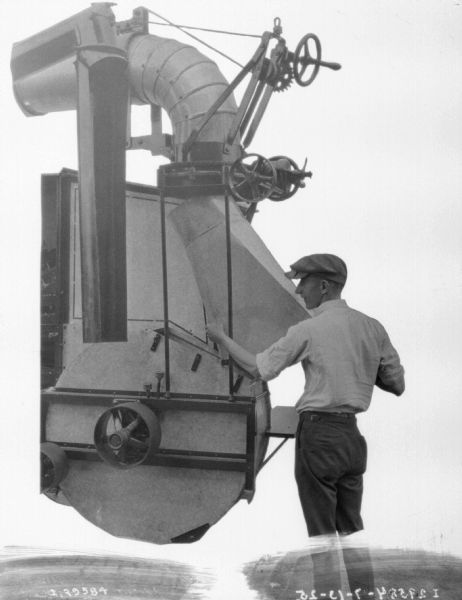 A man standing with a harvester thresher.
