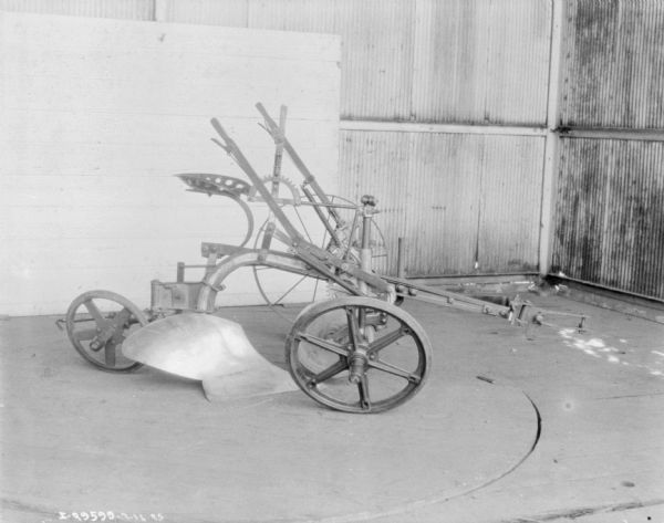 Sulky plow displayed on the floor of a building.