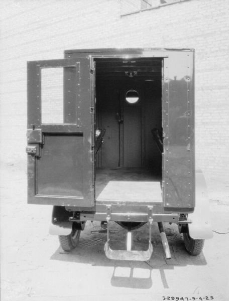 Rear view of truck with open door. In the background is a brick building.