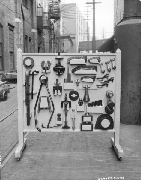 Tools on display on a board set up outdoors near factory buildings.