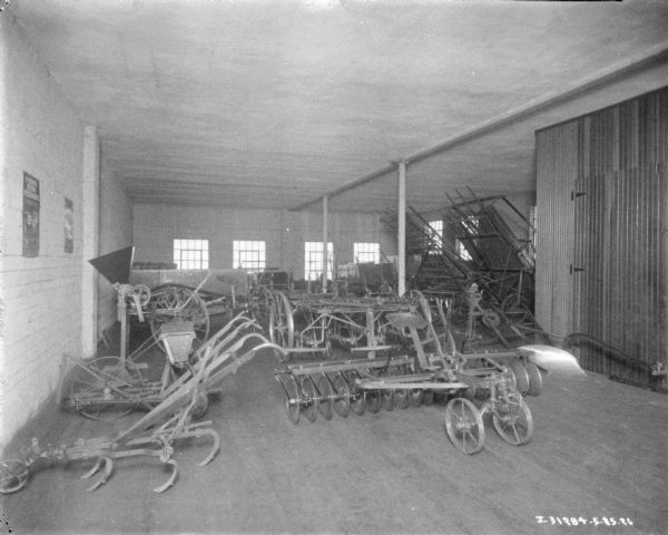 Interior view of dealership. Agricultural implements are displayed on the floor.