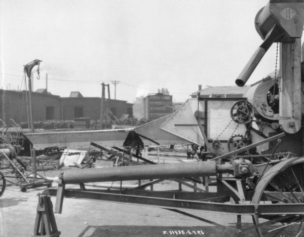 Close-up of a threshing machine outdoors in what appears to be a factory yard.