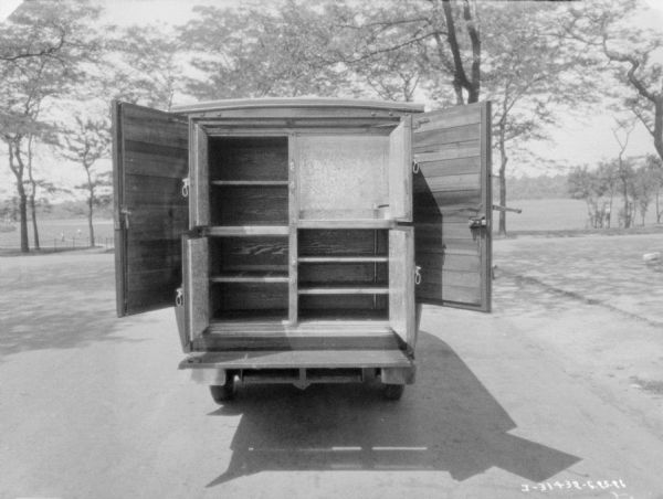 Rear view of a truck. There are four open doors showing the storage areas, some with shelves. There are two larger doors, also open, that when closed, would enclose the entire cabinet. 