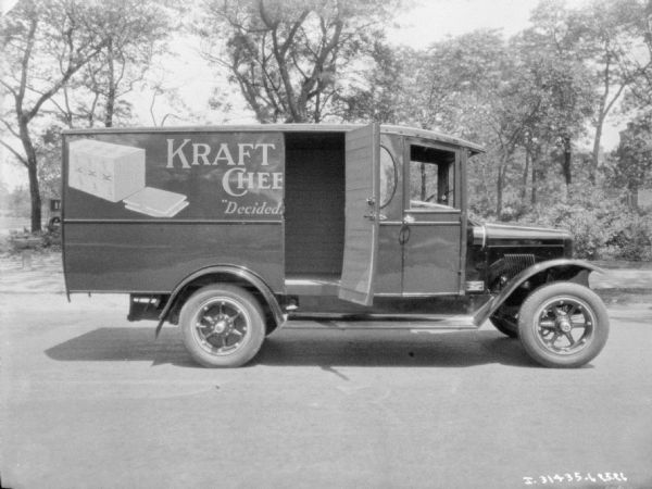 Right side profile view of a delivery truck with an open door. The sign on the side of the truck reads, in part: "Kraft Chee... 'Decided... ."