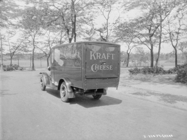 Three-quarter view from left rear of a delivery truck. The signs on the truck read: "Kraft Cheese 'Decidedly Better.'"