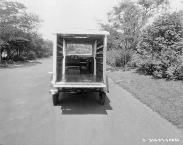 Rear view of a dairy delivery truck parked outdoors with the back door open, showing insulation. 