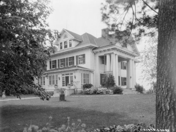 View across manicured lawn towards a large house with two-story columns.