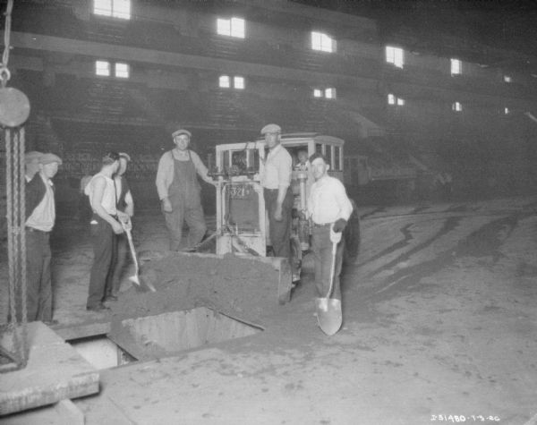 A group of men are using a tractor to prepare a baseball diamond.